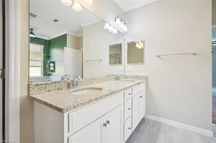 Bathroom featuring dual sinks, tile flooring, crown molding, and large vanity