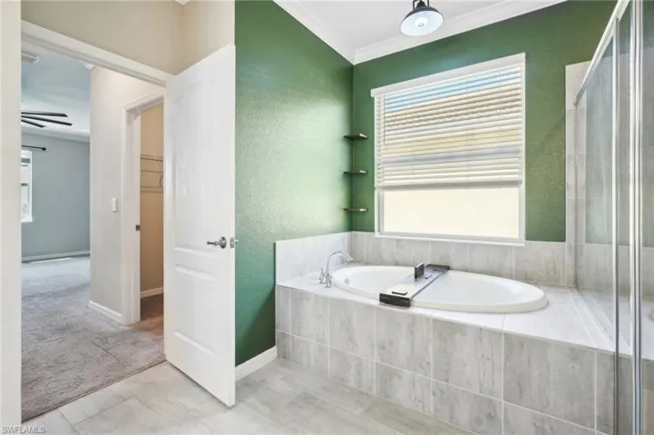 Bathroom with tile flooring, separate shower and tub, and crown molding.