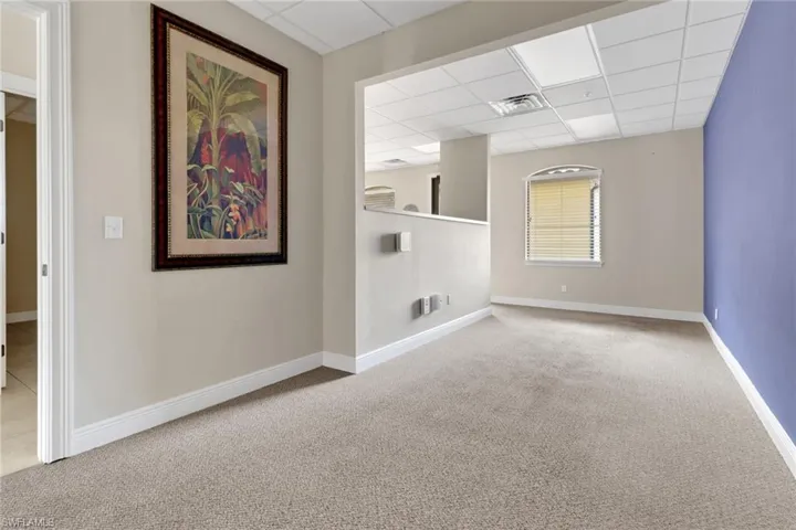 Carpeted spare room featuring a paneled ceiling