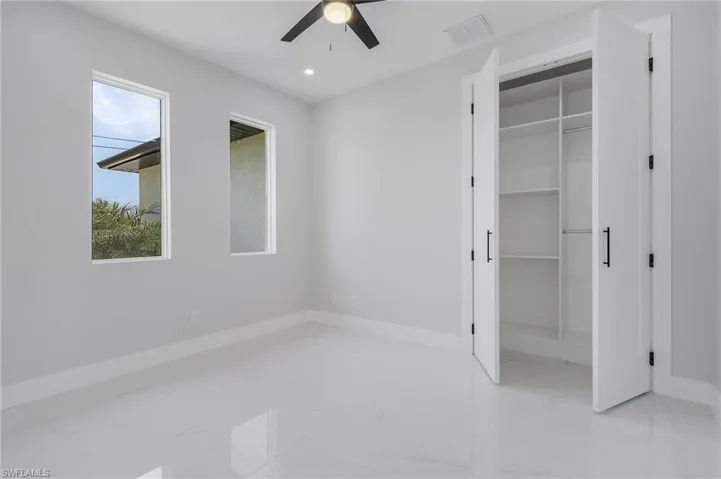 Unfurnished bedroom with multiple windows, a closet, light tile flooring, and ceiling fan