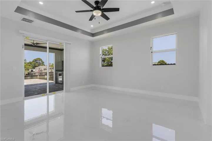 Empty room featuring ceiling fan, a raised ceiling, and light tile flooring