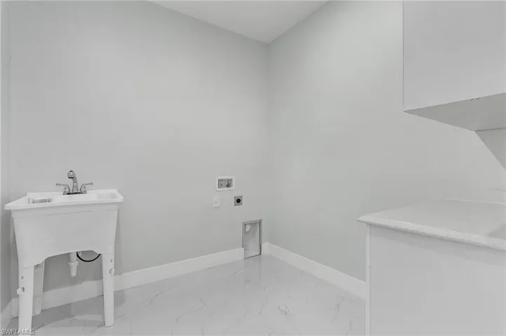 Washroom with hookup for a washing machine, light tile floors, and hookup for an electric dryer