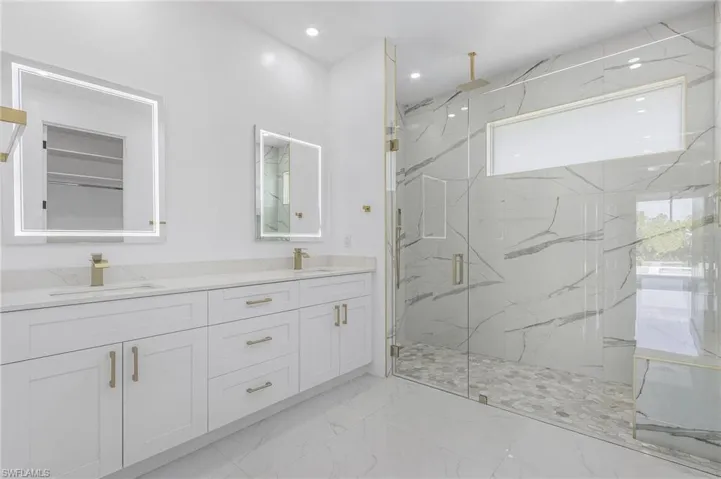 Bathroom featuring dual bowl vanity, tile floors, and a shower with door