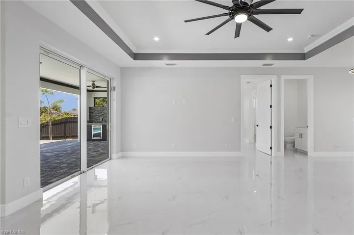 Spare room with a tray ceiling, ceiling fan, and light tile floors