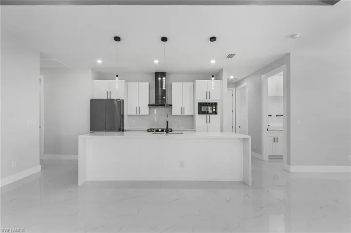 Kitchen with black appliances, light tile floors, and wall chimney exhaust hood