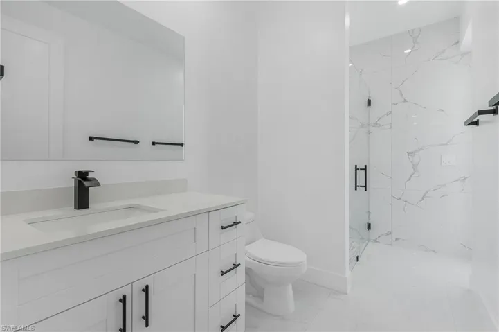 Bathroom featuring a tile shower, tile floors, toilet, and vanity