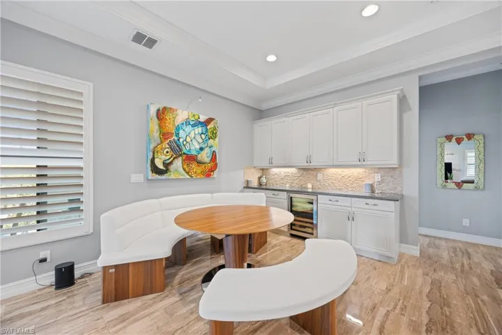 Dining space featuring crown molding, beverage cooler, recessed lighting, a raised ceiling, and a dry bar