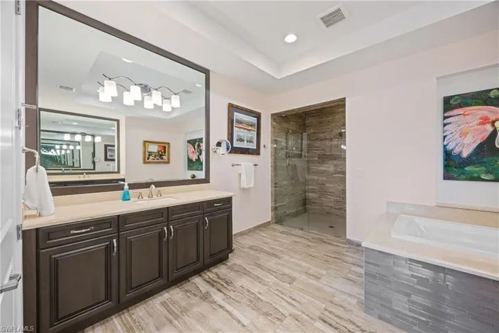 Bathroom with vanity, a stall shower, a bath, a raised ceiling, and recessed lighting