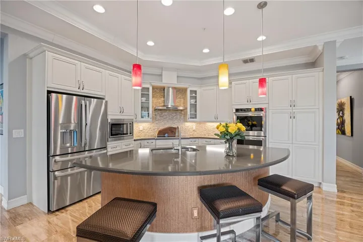 Kitchen with stainless steel appliances, dark countertops, white cabinets, a breakfast bar, and crown molding