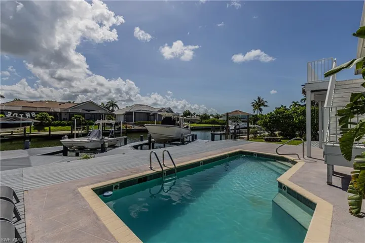 Outdoor pool with boat lift, a dock, and a water view