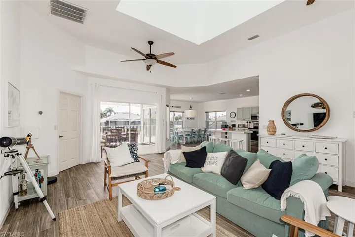 Living area featuring a ceiling fan, light wood-style flooring, and a skylight