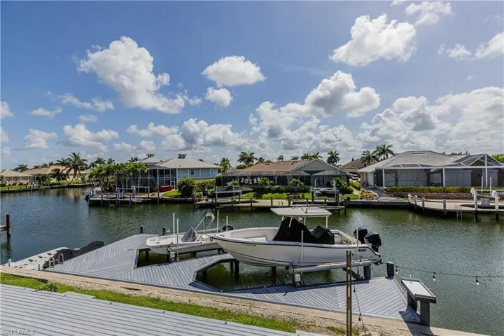 Dock with boat lift, a residential view, and a water view