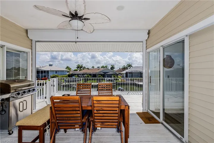 Wooden deck with a ceiling fan, a residential view, a water view, outdoor dining area, and area for grilling
