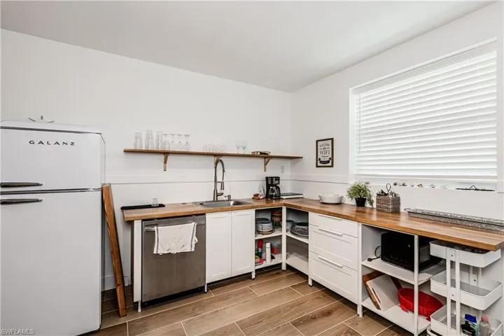 Kitchen with freestanding refrigerator, open shelves, and wood counters