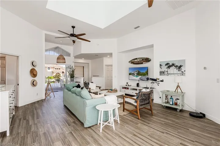 Living room with ceiling fan, a towering ceiling, and wood finished floors