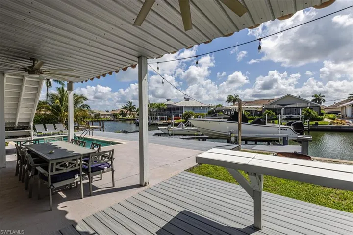 Wooden deck with ceiling fan, a water view, a boat dock, and boat lift
