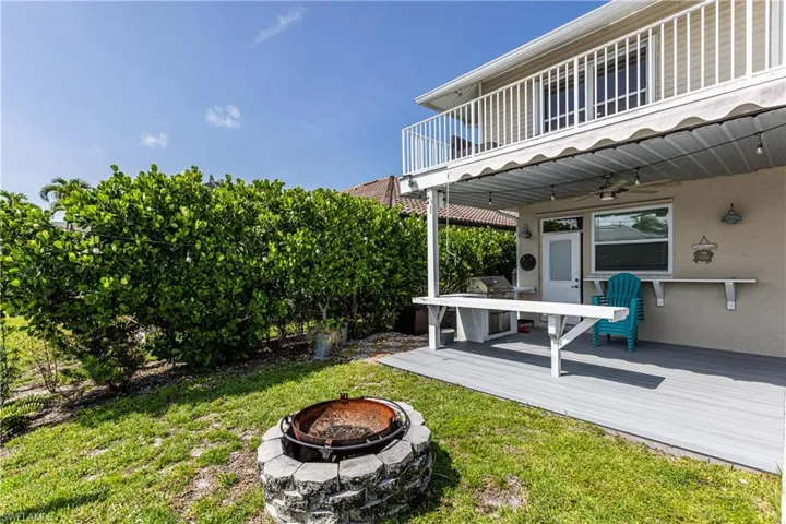 View of green lawn featuring a fire pit, a ceiling fan, and a wooden deck