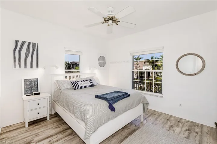 Bedroom with multiple windows, light wood-type flooring, and ceiling fan