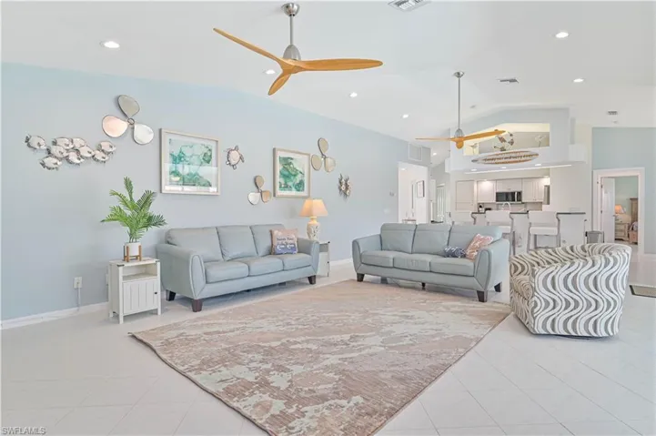 Living room featuring light tile patterned floors, ceiling fan, and high vaulted ceiling