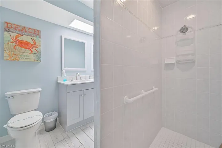 Bathroom featuring vanity, tiled shower, and toilet