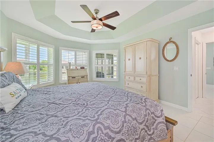 Tiled bedroom with a tray ceiling and ceiling fan