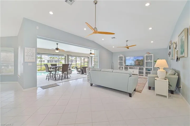 Living room featuring vaulted ceiling, light tile patterned floors, and ceiling fan
