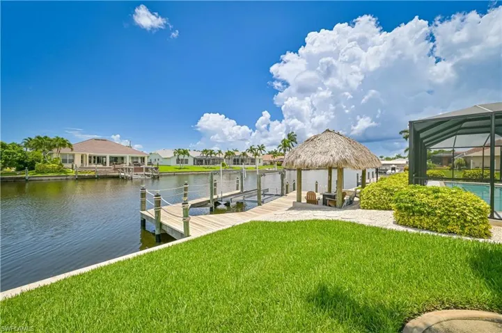 Dock area with a yard, a water view, and glass enclosure