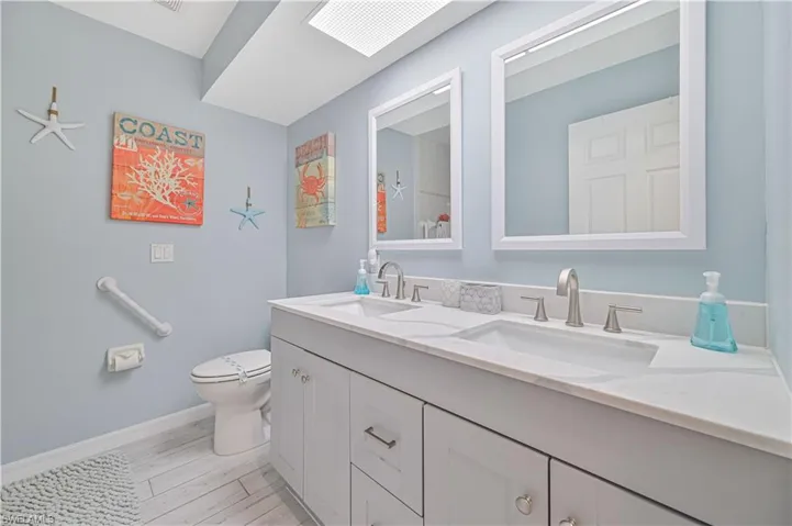 Bathroom with hardwood / wood-style flooring, toilet, and double sink vanity