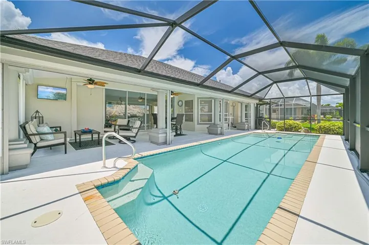 View of swimming pool with outdoor lounge area, glass enclosure, ceiling fan, and a patio area