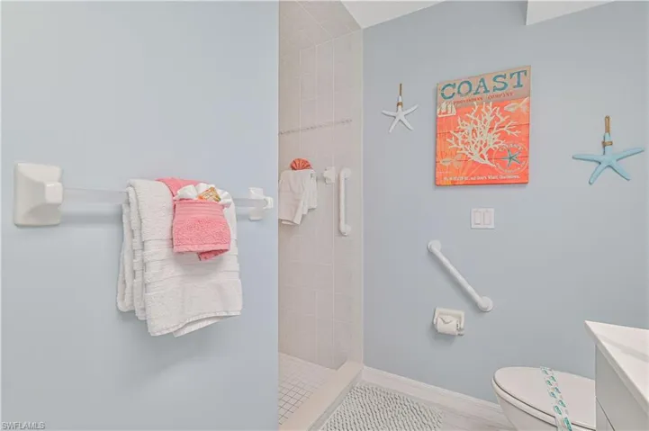 Bathroom with toilet, vanity, and a tile shower