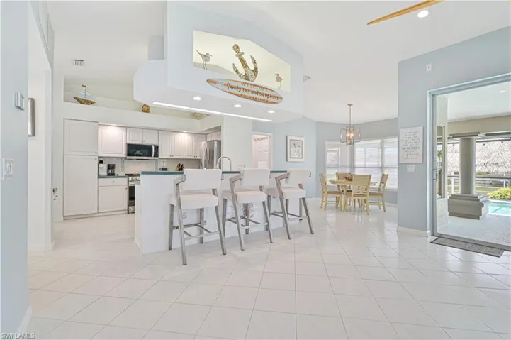 Kitchen with plenty of natural light, appliances with stainless steel finishes, light tile patterned flooring, and a kitchen breakfast bar