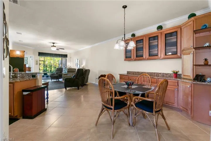 Dining room with light tile patterned flooring, ceiling fan with notable chandelier, and ornamental molding