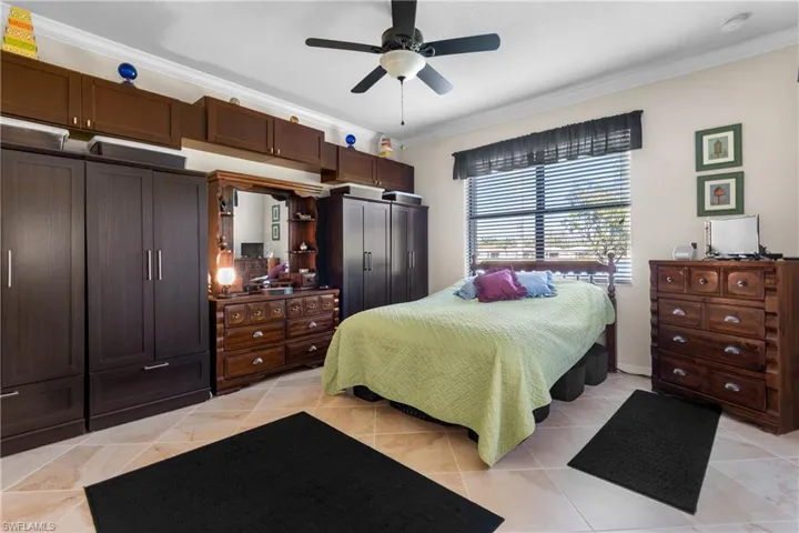 Tiled bedroom with ceiling fan and ornamental molding
