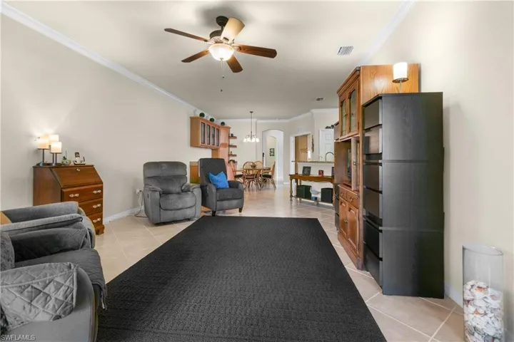 Tiled living room featuring ceiling fan and crown molding
