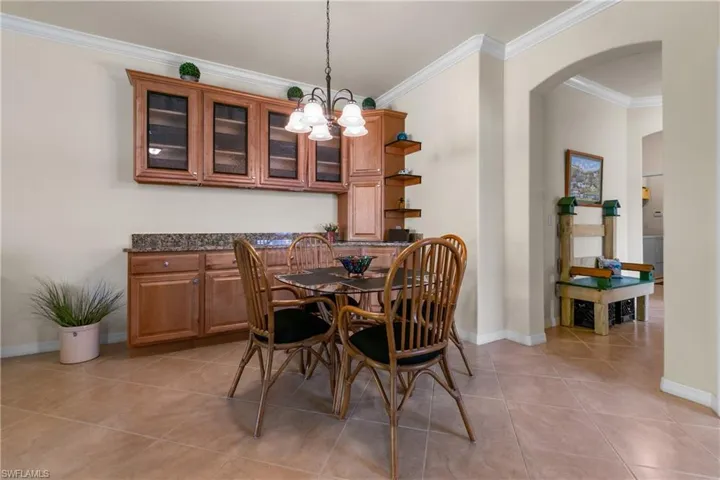Tiled dining area with crown molding and a chandelier