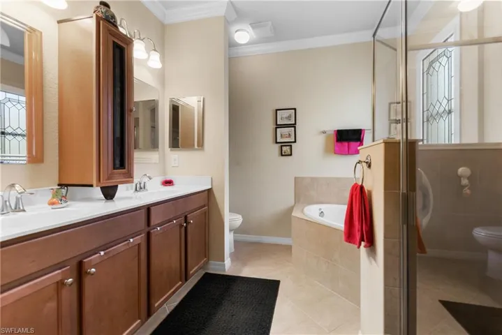 Full bathroom with tile patterned flooring, plus walk in shower, toilet, and ornamental molding
