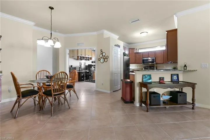 Kitchen with kitchen peninsula, light tile patterned floors, ornamental molding, and appliances with stainless steel finishes