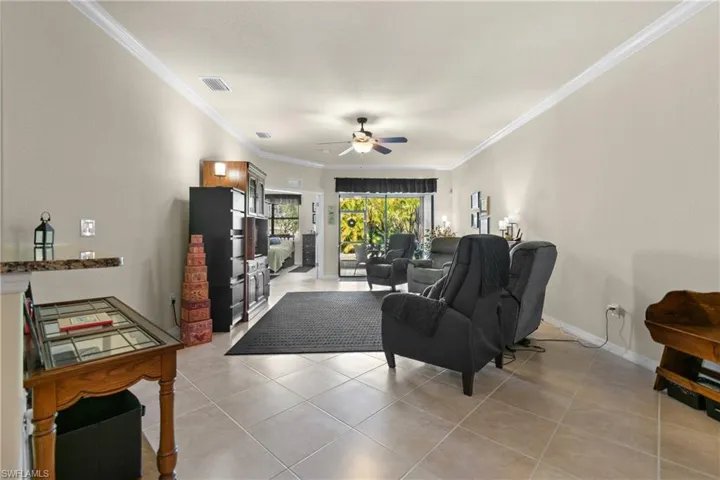 Living room featuring ceiling fan, light tile patterned flooring, and ornamental molding