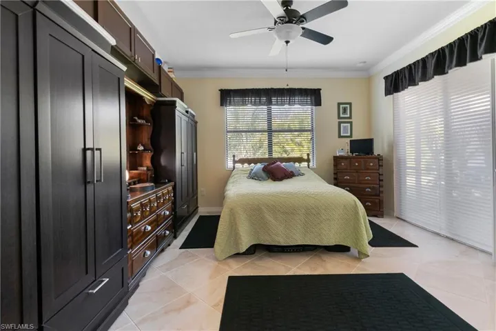 Bedroom with ceiling fan, crown molding, and light tile patterned floors