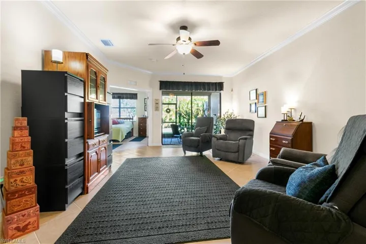 Living room with light tile patterned floors, ceiling fan, and ornamental molding