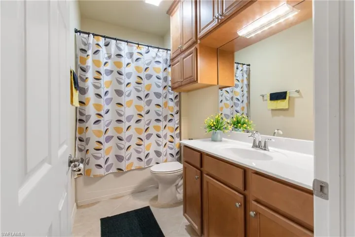 Full bathroom featuring tile patterned flooring, shower / bath combo, toilet, and vanity