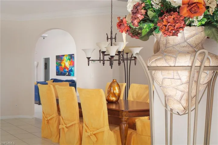 Tiled dining area with crown molding and a chandelier