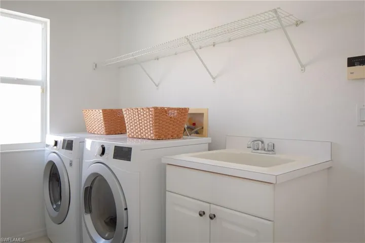 Washroom featuring cabinets, sink, and independent washer and dryer
