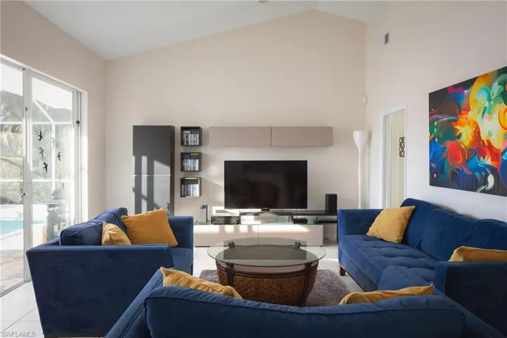 Living room with light tile patterned flooring and high vaulted ceiling