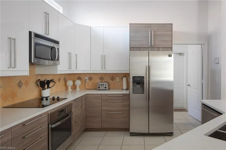 Kitchen featuring white cabinetry, light tile patterned floors, tasteful backsplash, and appliances with stainless steel finishes