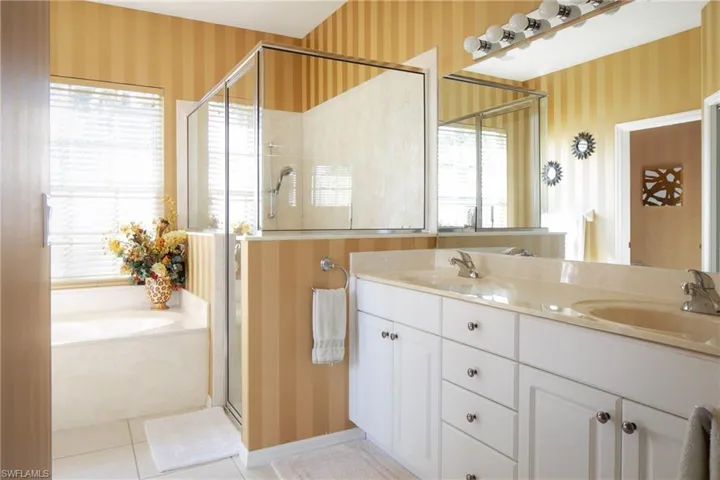 Bathroom with tile patterned flooring, vanity, a wealth of natural light, and plus walk in shower
