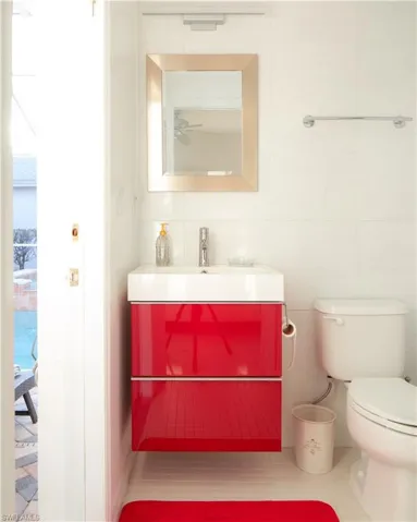 Bathroom with vanity, ceiling fan, tile walls, and toilet