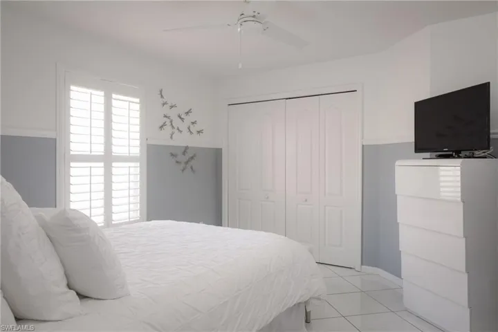 Tiled bedroom featuring ceiling fan and a closet