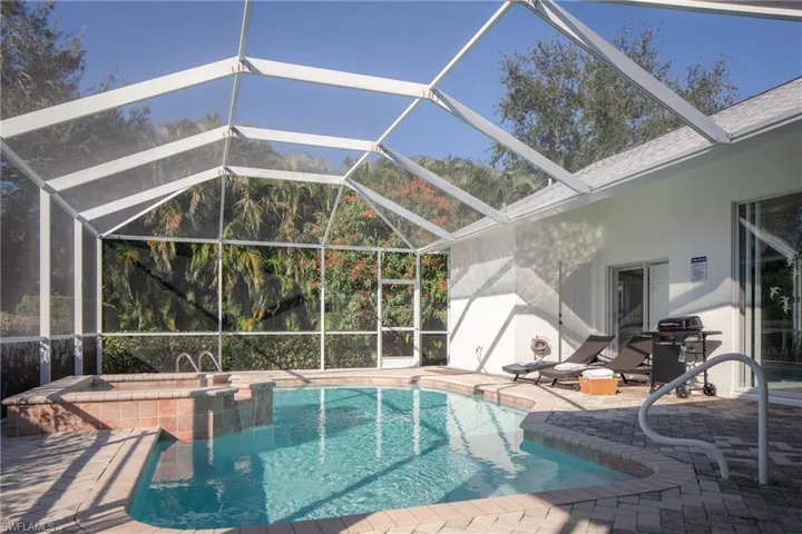View of pool with area for grilling, a patio area, and glass enclosure