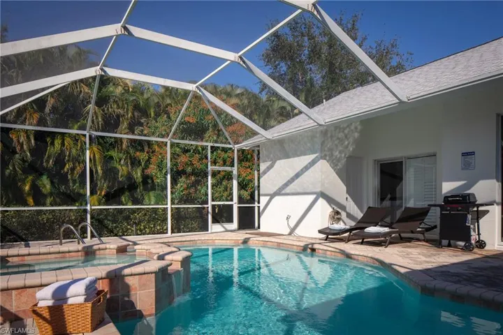View of pool with a grill, a patio area, and glass enclosure